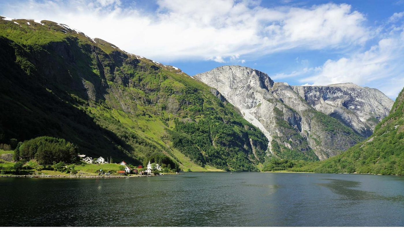 The white wooden church of Bakka from 1859 among the village houses at the fjord