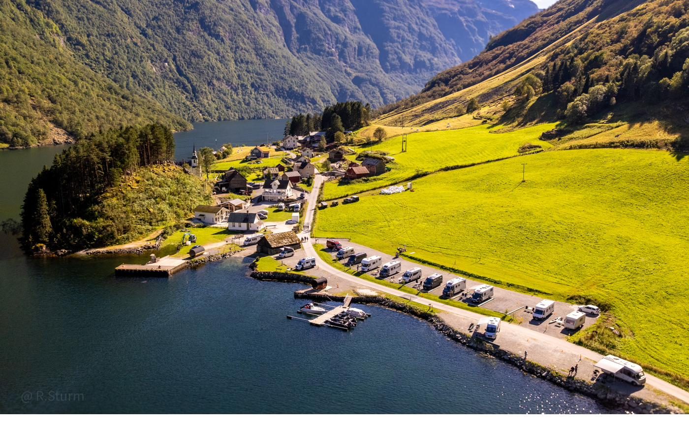 Drone view of the campervan pitches along the fjord shore at Bakka, the village behind