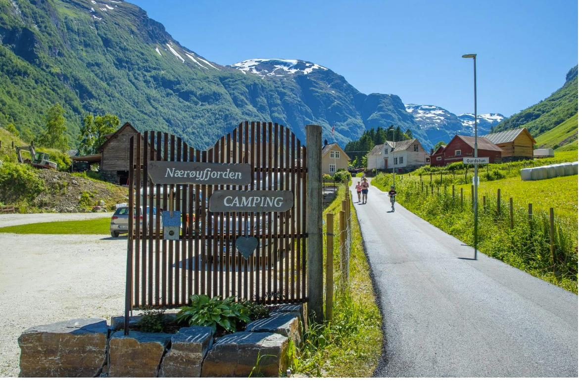 The wooden entrance gate of Nærøyfjorden Camping beside the village road in Bakka