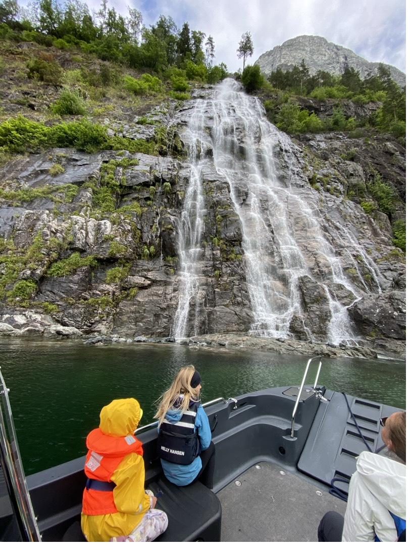 Two children in life jackets watching a waterfall from the family's boat