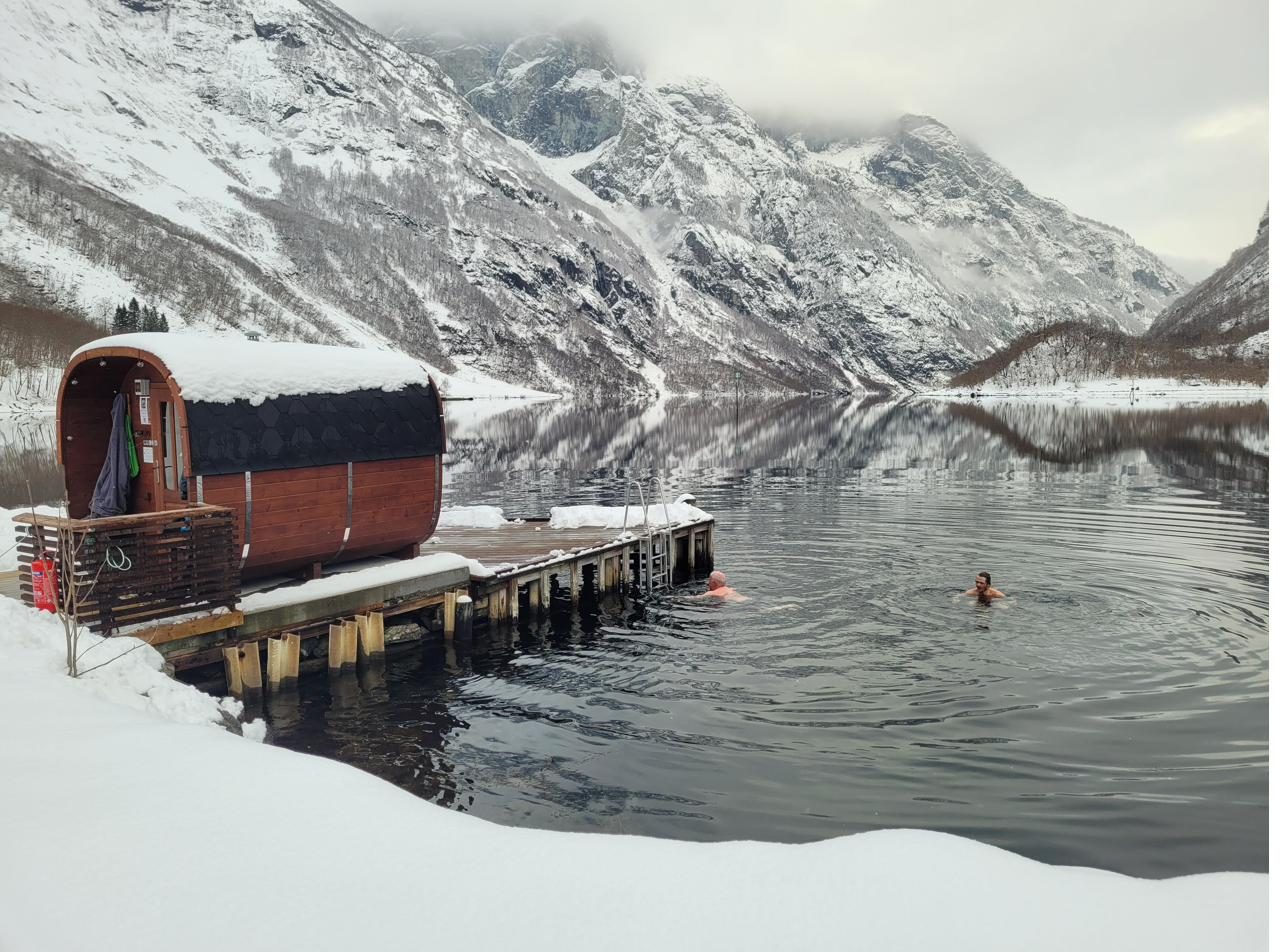 A winter swimmer by the sauna, snow on the mountains across the fjord